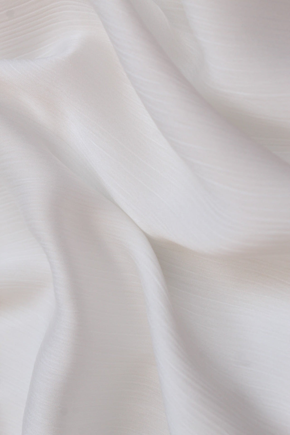 A white silk hijab with a crinkled texture on one side and a matte finish on the other, providing a non-slip fit.