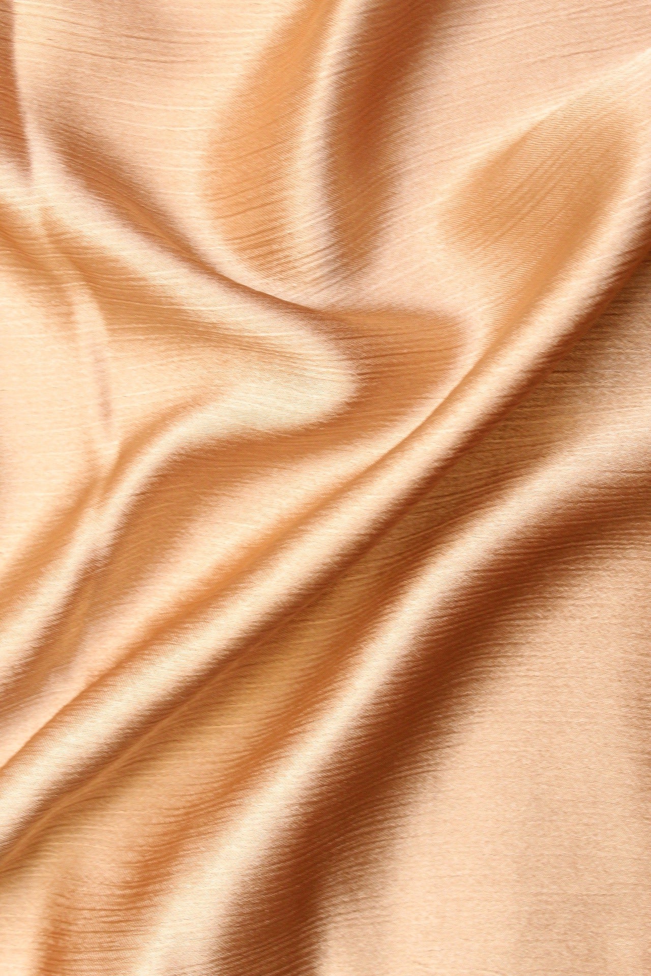 A silk hijab in a sand color, displaying a crinkled texture on one side and a matte finish on the other.