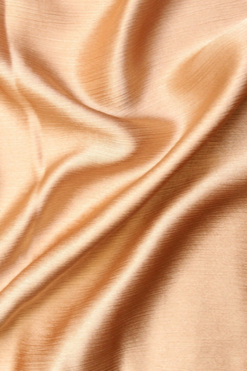 A silk hijab in a sand color, displaying a crinkled texture on one side and a matte finish on the other.
