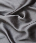 A luxurious silk hijab in a smoke gray color, showing a crinkled texture on one side and a matte finish on the other, highlighting its dual-texture design.